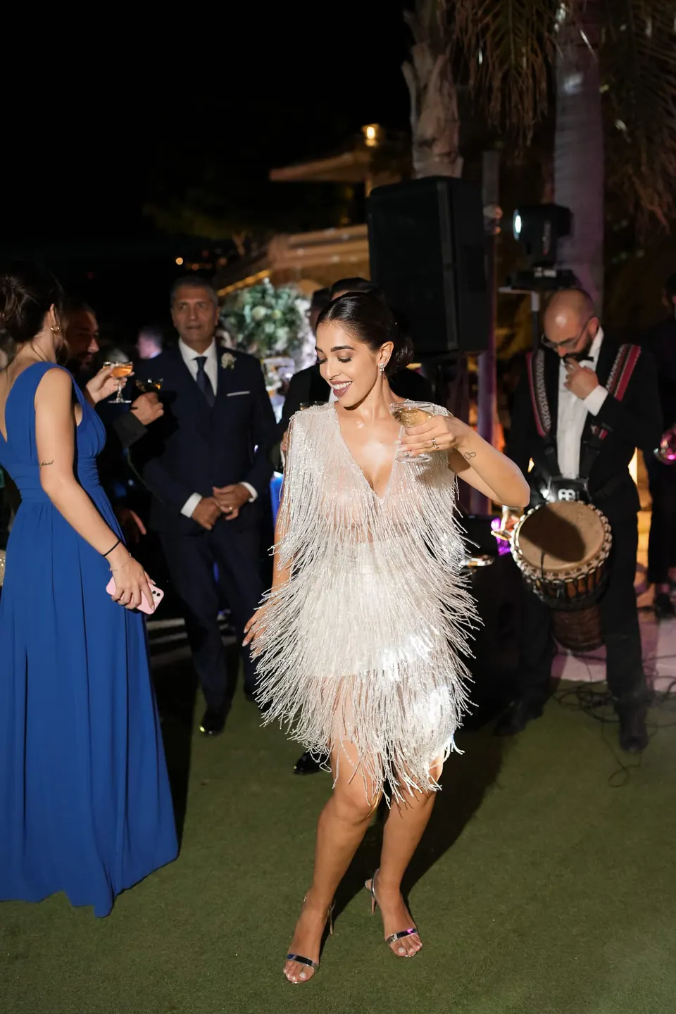Bride in a fringed party dress dancing with guests at night at Villa Scalera in Bacoli.