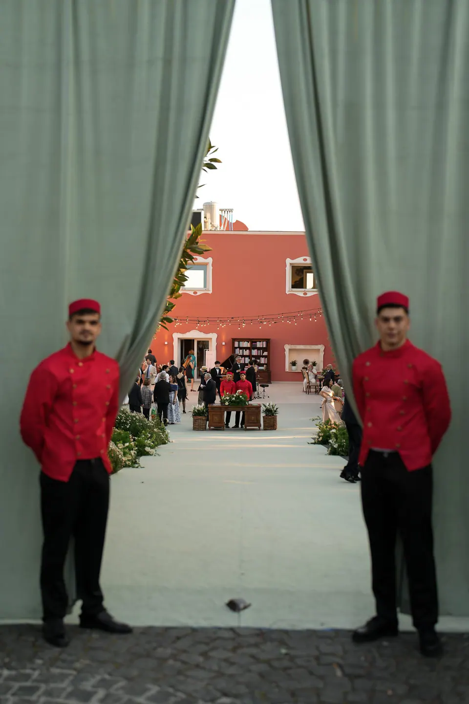 Dos camareros con chaqueta roja en la entrada del banquete.