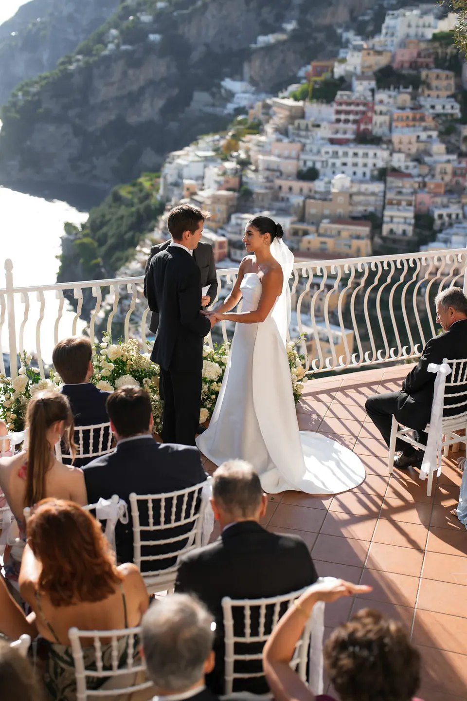 Bride and groom at the altar, guests seated on the terrace facing Positano.