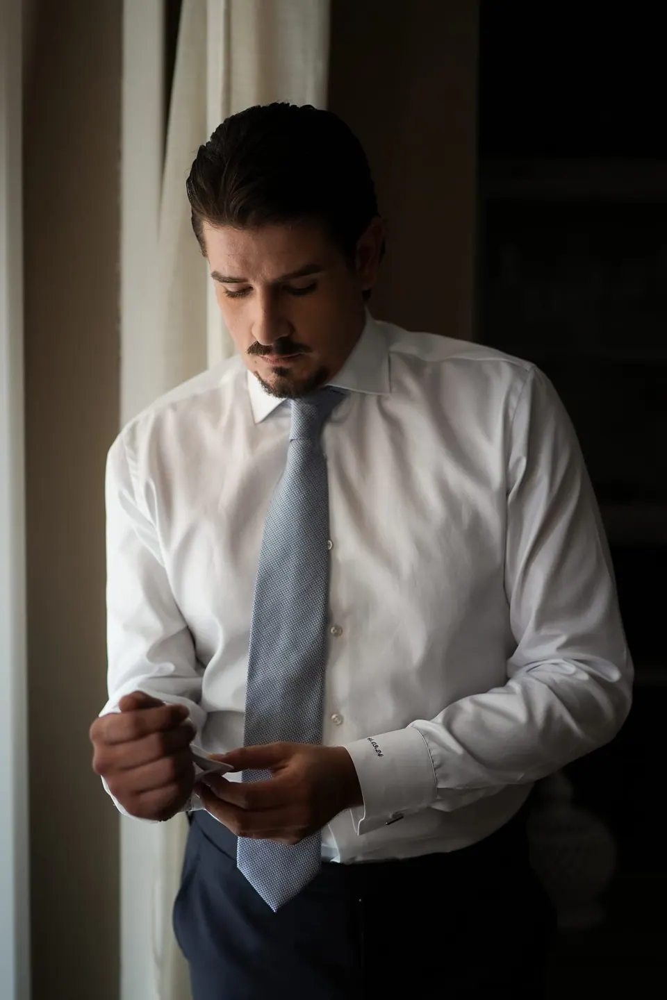 Groom in a white shirt loosening his tie after dinner at Tenuta San Domenico.