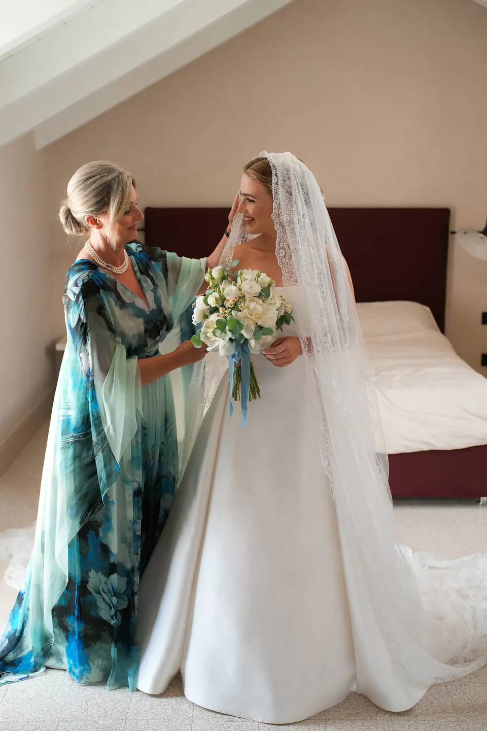 Die Mutter richtet im Dachzimmer den Schleier der Braut.