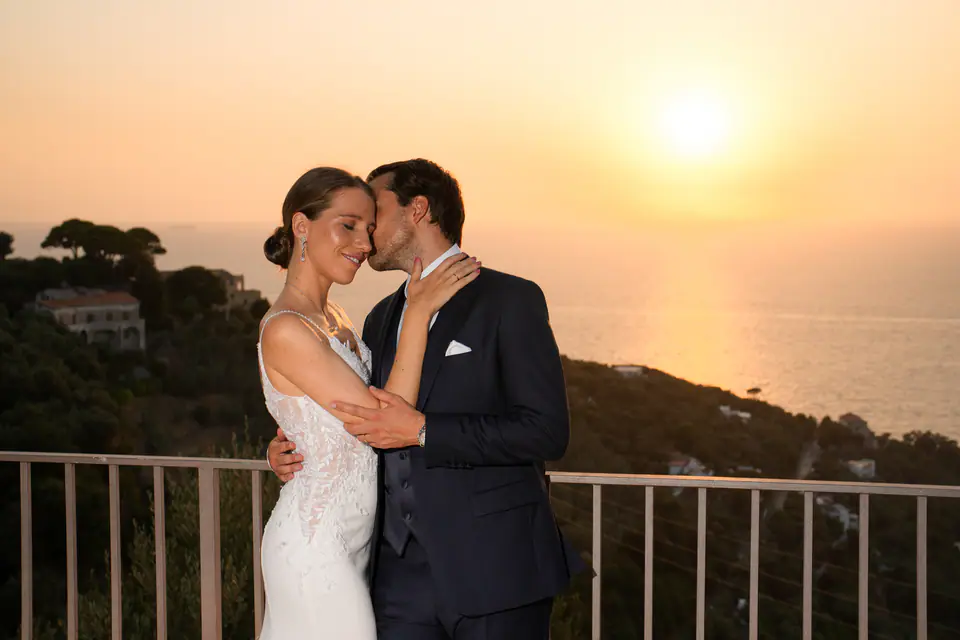 Couple embracing at a railing as the sun goes down over the sea of Massa Lubrense.