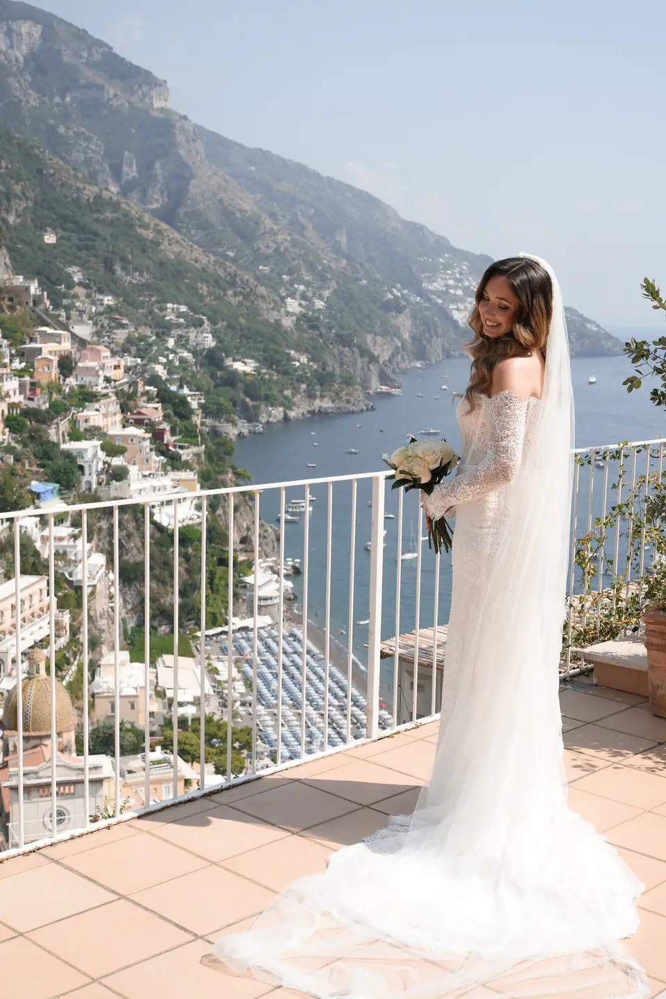 Bride with her bouquet at the railing of a terrace above Positano.