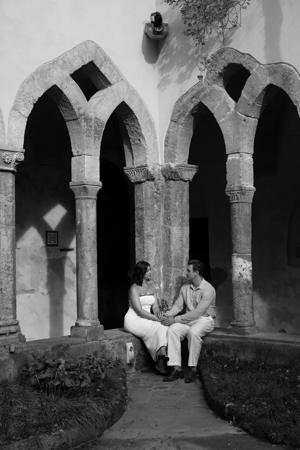 Black and white photo of the couple sitting in a medieval cloister in Sorrento.