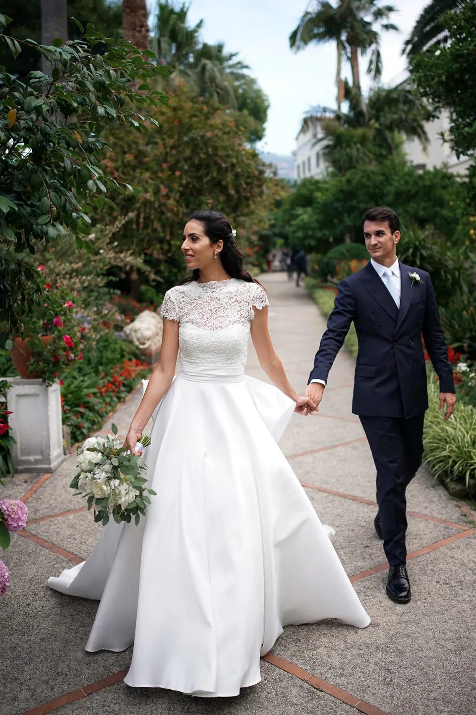 Bride and groom walking down a garden path at La Cocumella