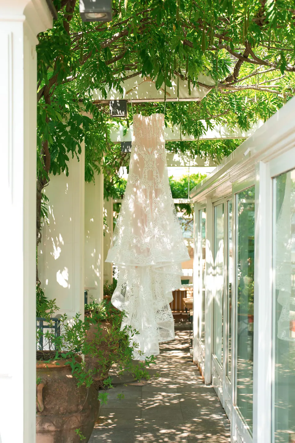 Das Spitzenkleid hängt zwischen den Weinranken am Ende der Glasveranda.