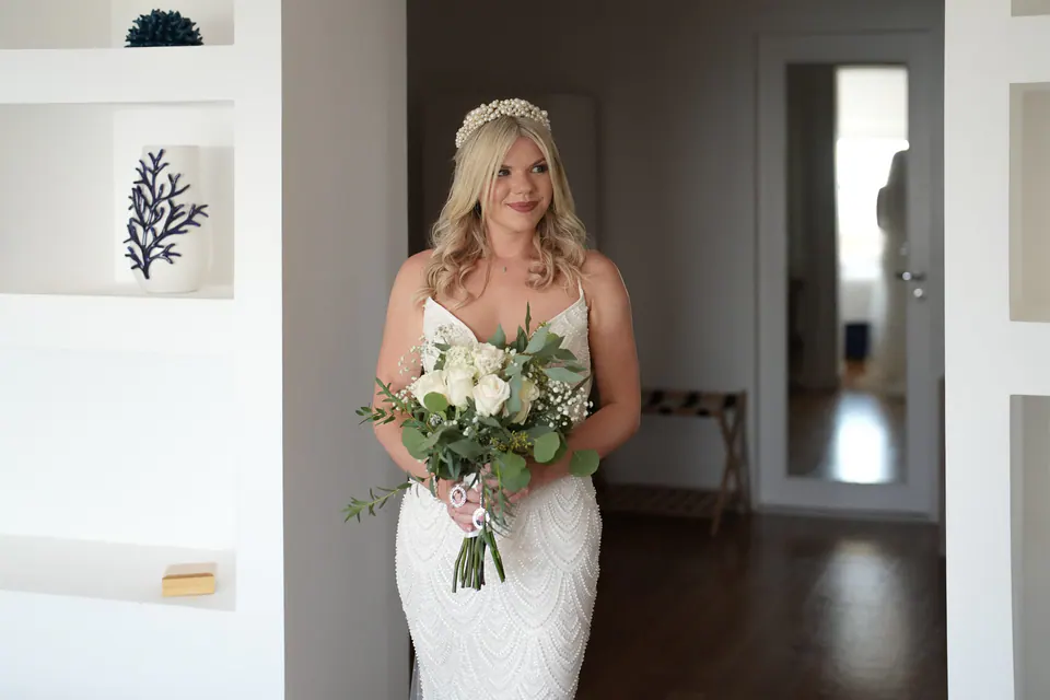 La sposa con il bouquet in una porta bianca