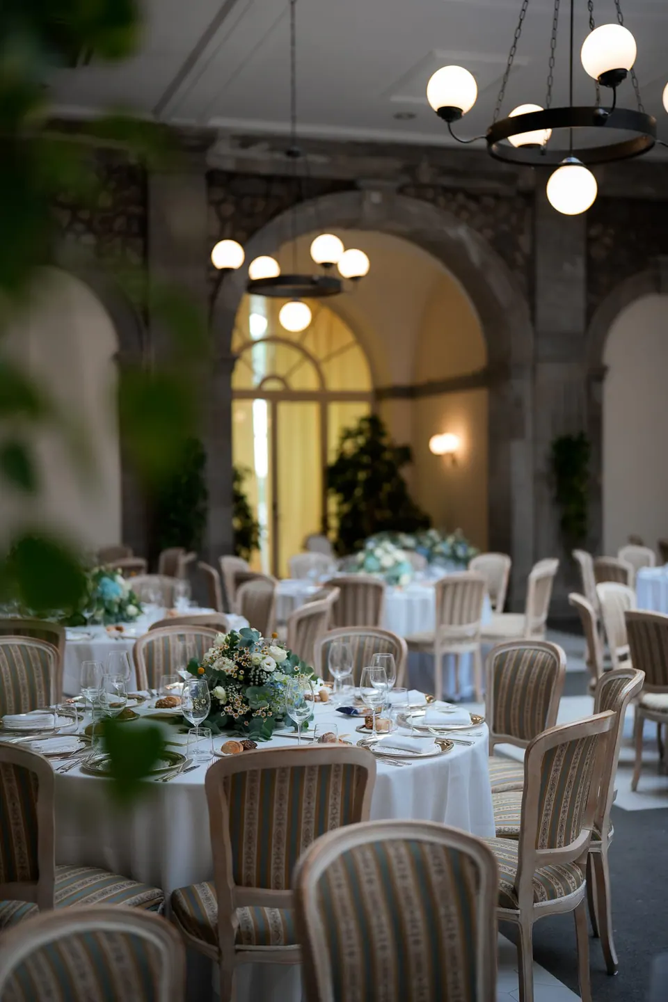Runde Dinnertische unter den Bögen und Lampen des Kreuzgangs im La Cocumella.