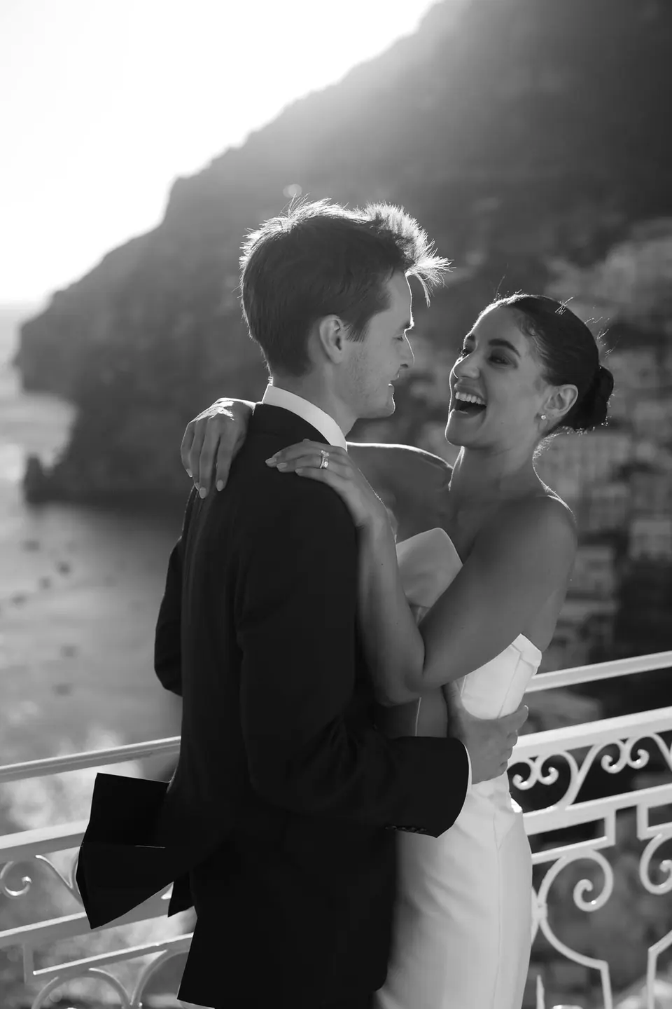Black and white photo of the couple laughing at the railing.