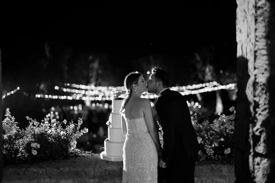 Couple sharing a kiss under a canopy of lights, closing their celebration under the stars.