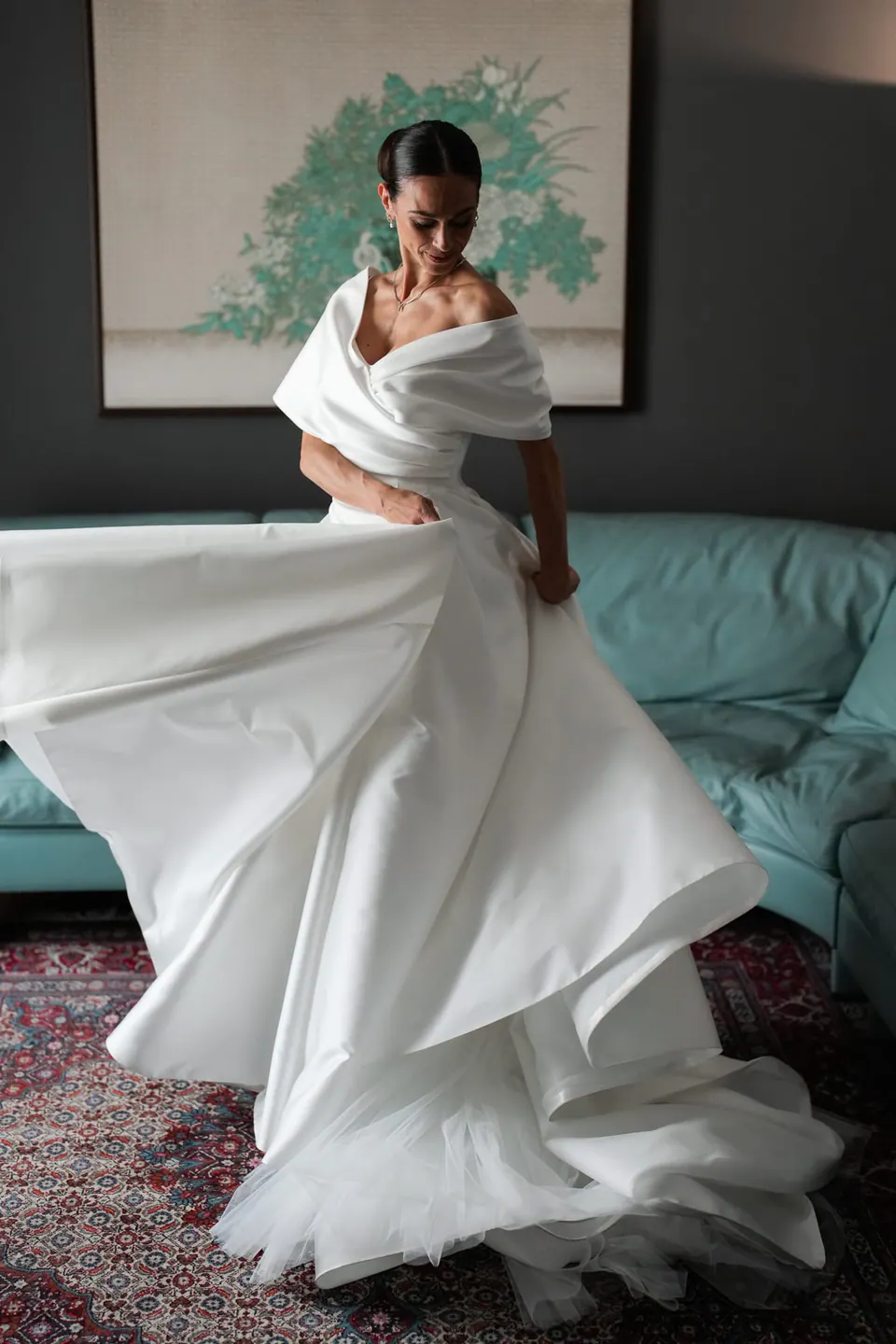 Sposa che fa volteggiare l'ampia gonna in una stanza con un divano turchese.