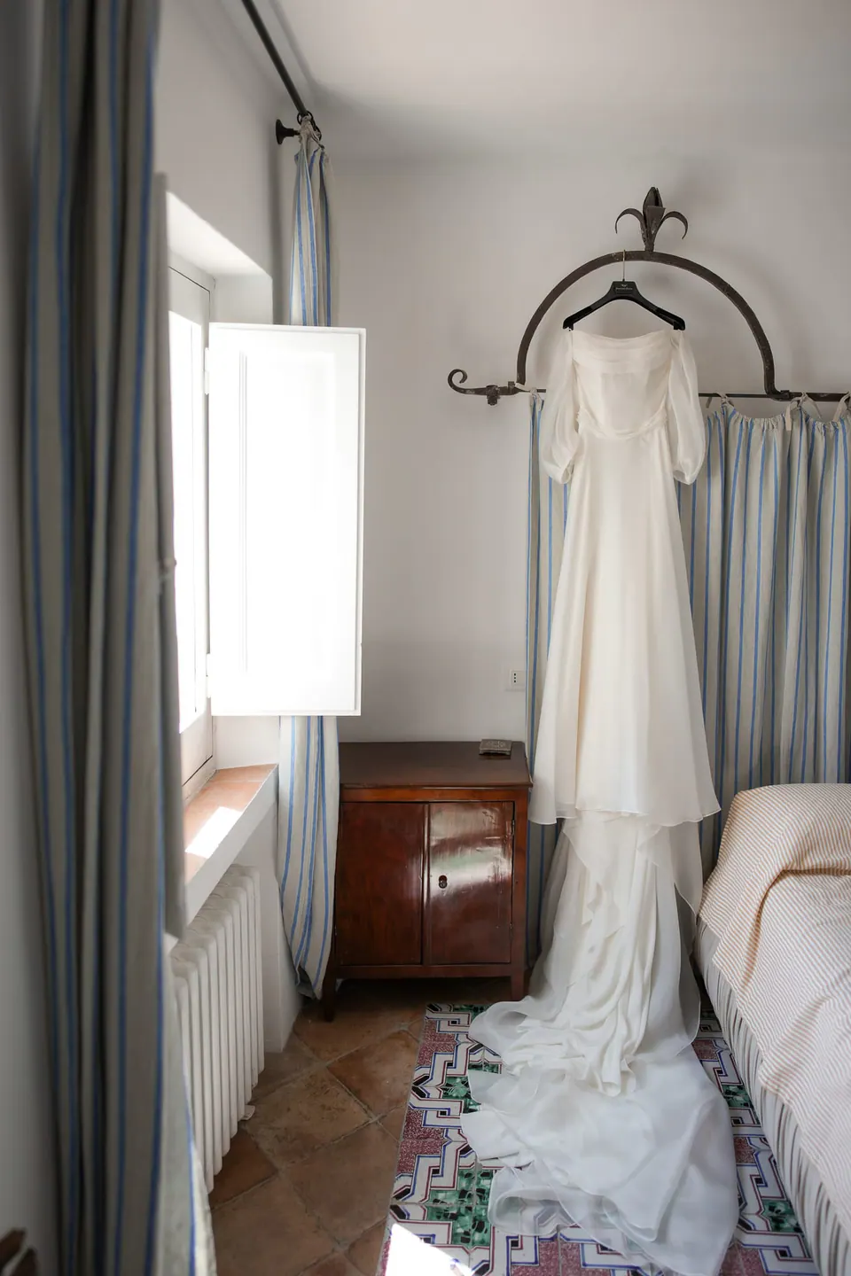 Das Brautkleid in einem hellen Schlafzimmer mit gemustertem Fliesenboden.