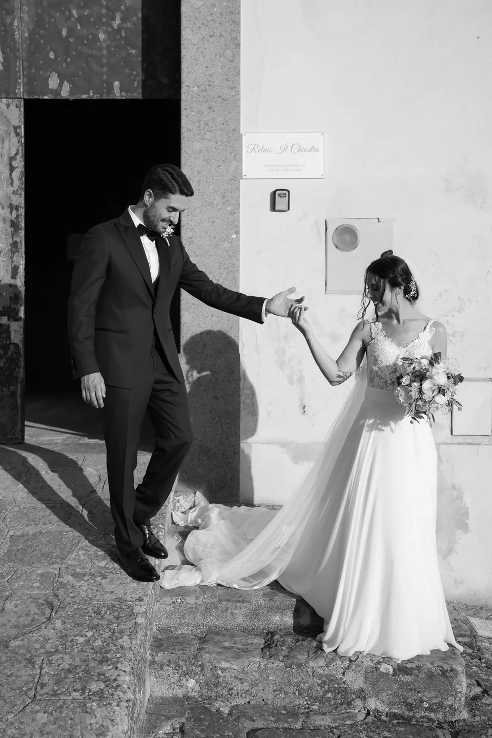 Black and white photo of the groom leading the bride out through the church door.
