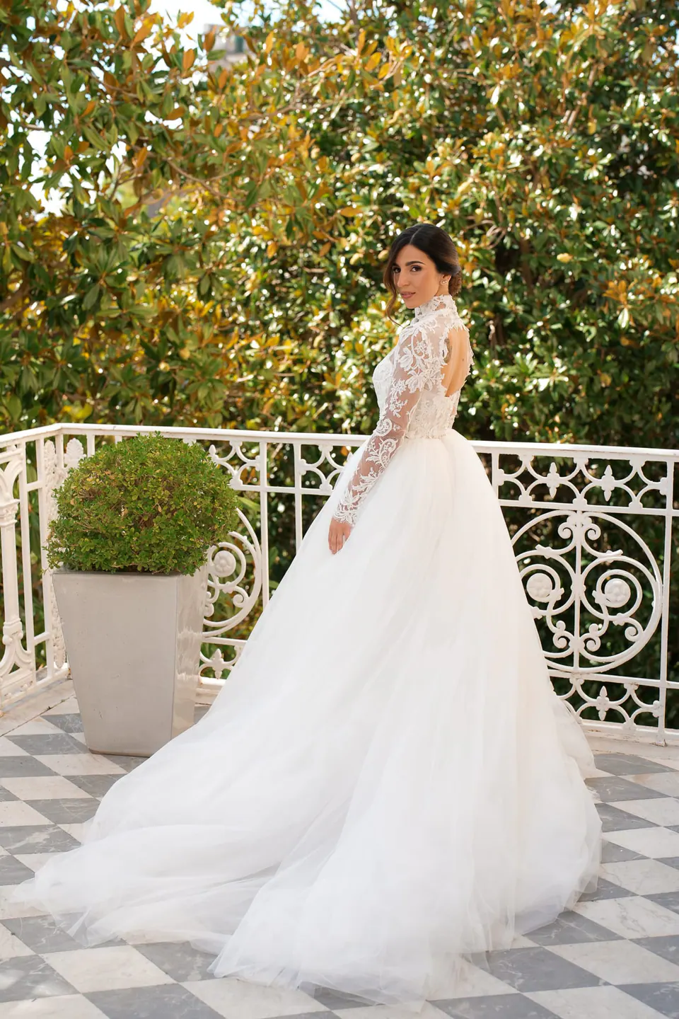 Bride in a tulle gown on a balcony with a white wrought-iron railing