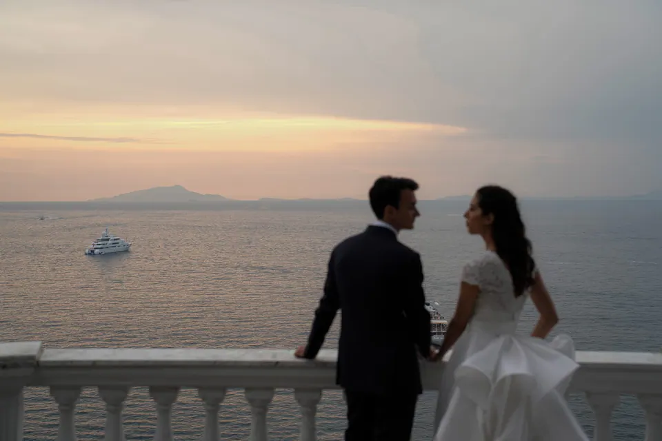 Bride and groom watching the sunset together from the terrace, Capri island on the horizon — poetic ending to their Sorrento wedding.