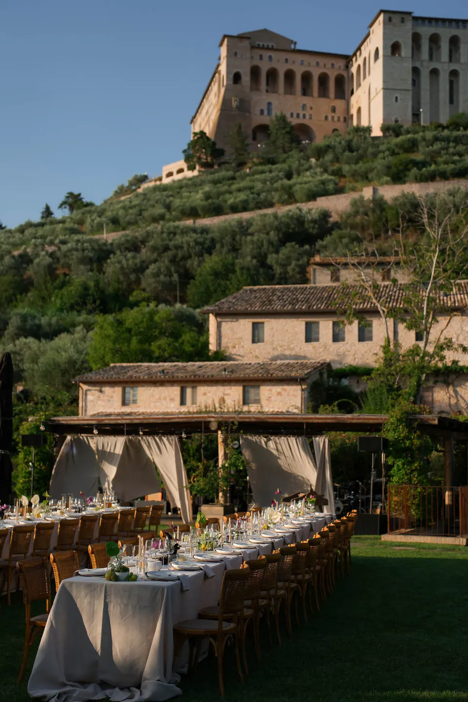 Dinner tables on the lawn with the borgo and Assisi on the hill above