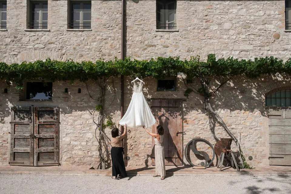 The wedding dress hanging on the stone wall of the farmhouse