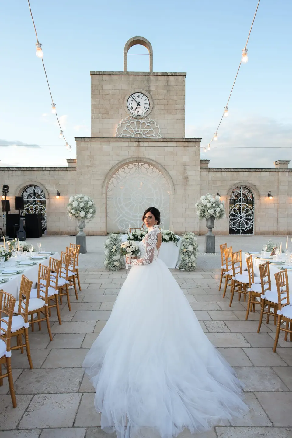 Bride in the courtyard set for dinner, the clock tower behind