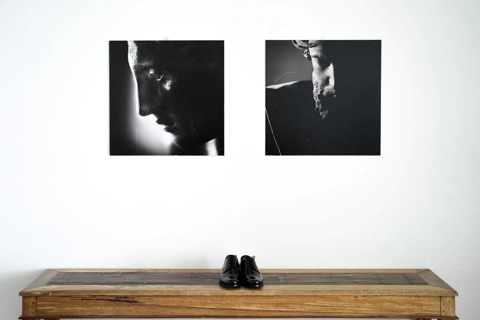 Le scarpe dello sposo su una consolle in legno sotto due ritratti in bianco e nero.