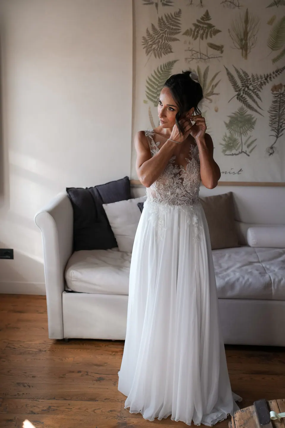 Bride fixing her earring in a room with botanical prints