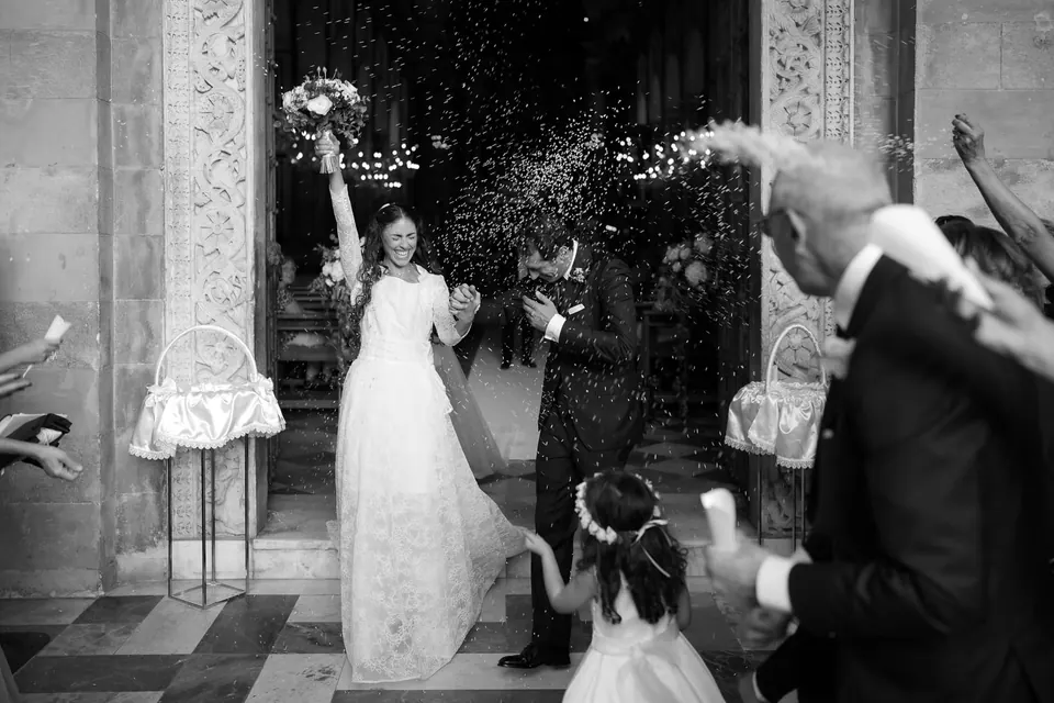 Black and white photo of the newlyweds leaving the church as guests throw rice.