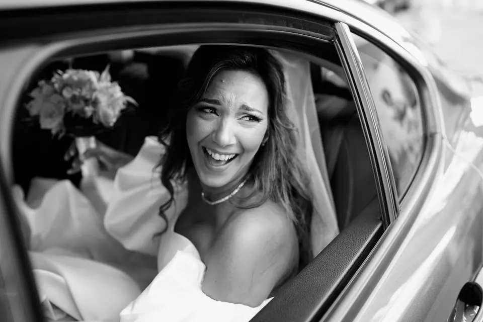 Bride smiling from the car window, filled with joy and anticipation.