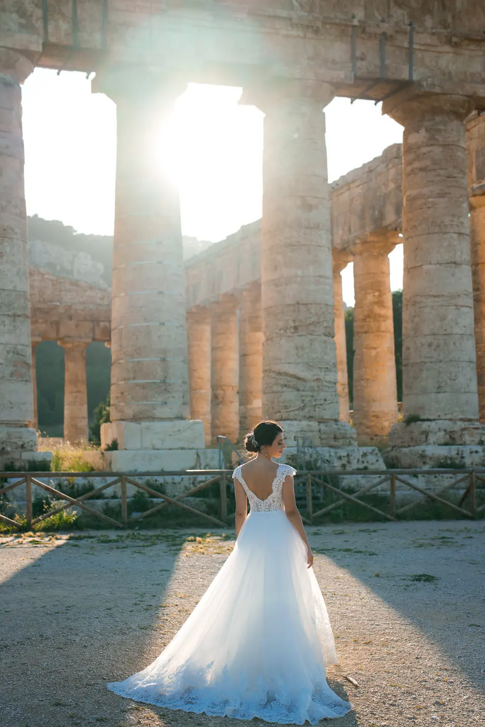 Bride seen from behind among the columns of an ancient Greek temple