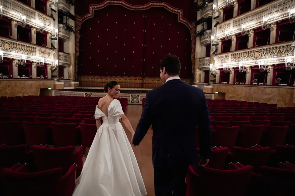 Sposi di spalle che salgono sul palcoscenico del Teatro San Carlo.