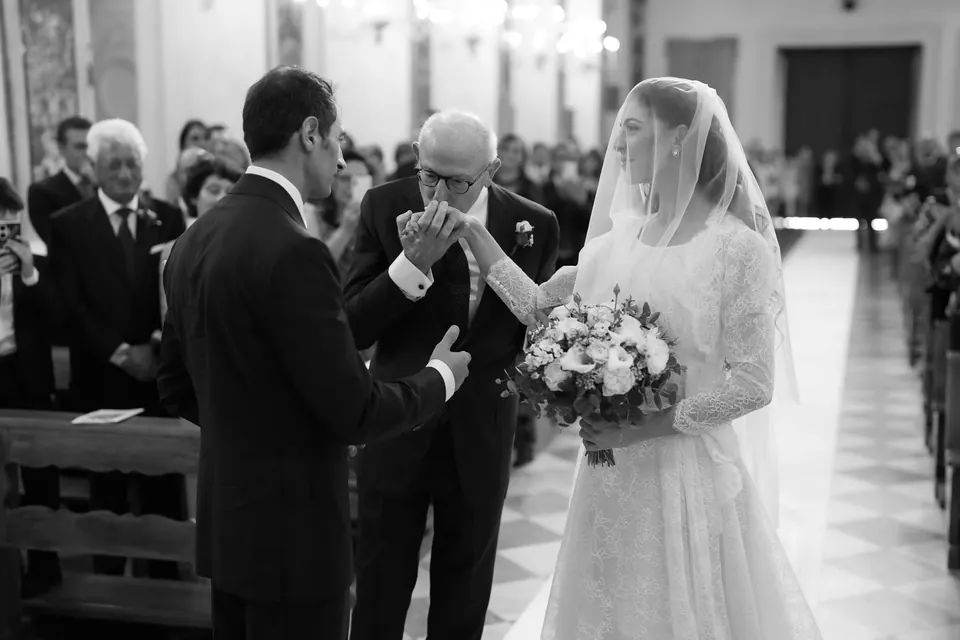Black and white photo of the father giving the bride to the groom at the altar.