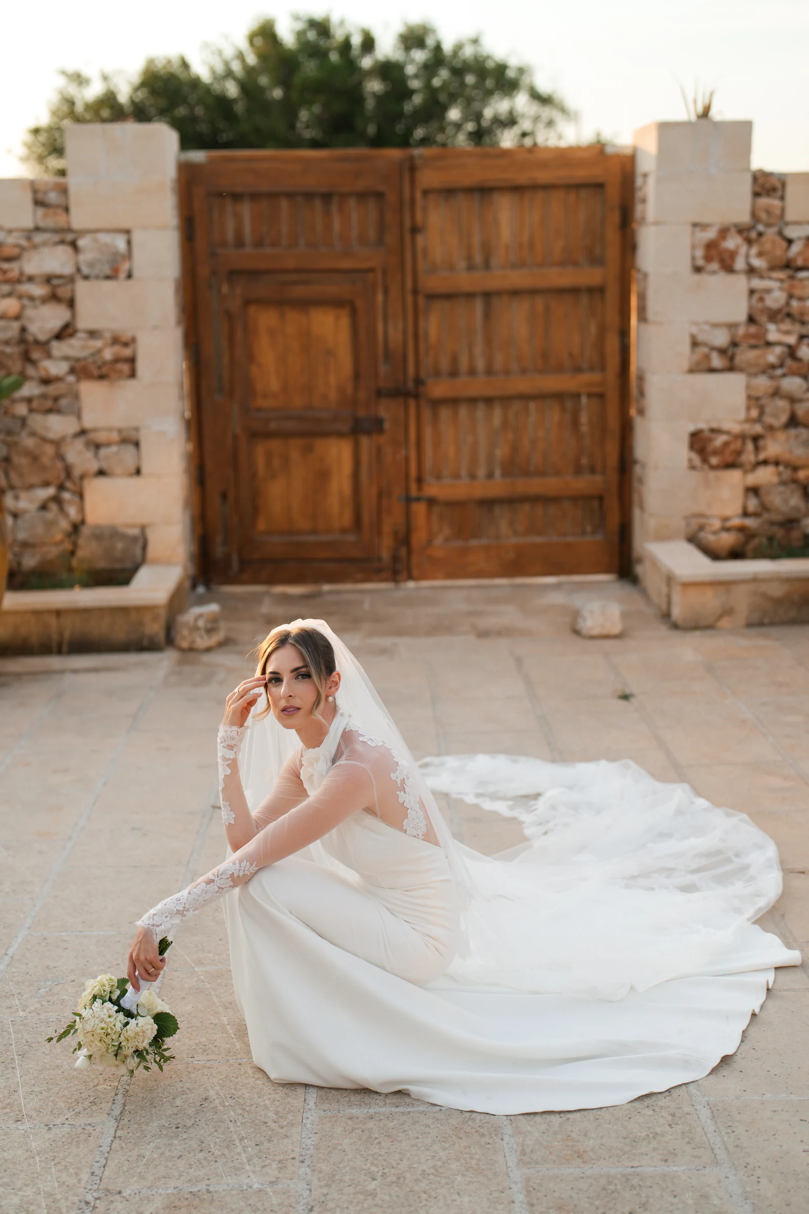 La sposa accovacciata sul selciato di Tenuta Sant'Elia, con lo strascico aperto intorno a sé.