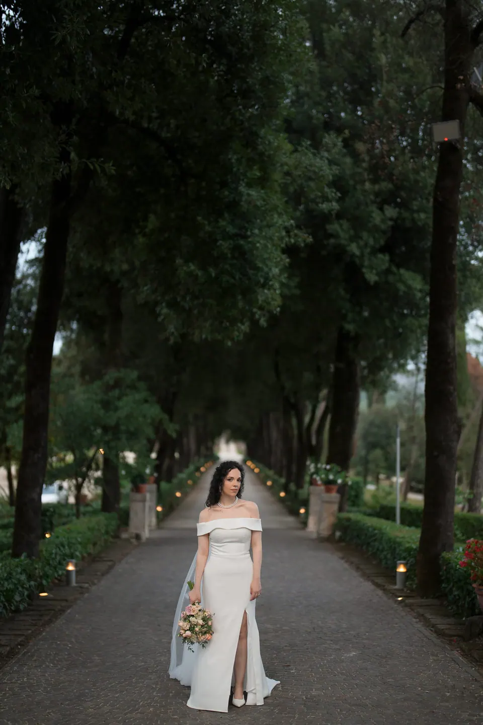 La novia baja sola por la avenida de cipreses de Villa Ortensia D’Avalos antes de los votos.