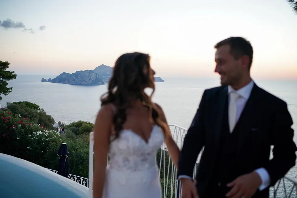 Sposi accanto alla piscina al tramonto, Capri in lontananza.