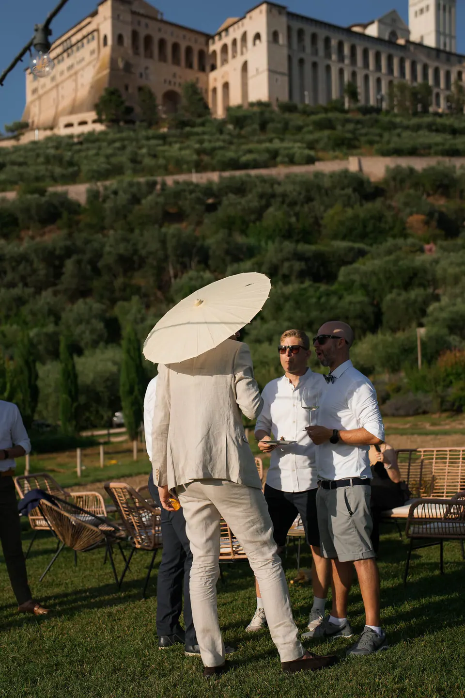 Guests with a white parasol on the lawn below the borgo