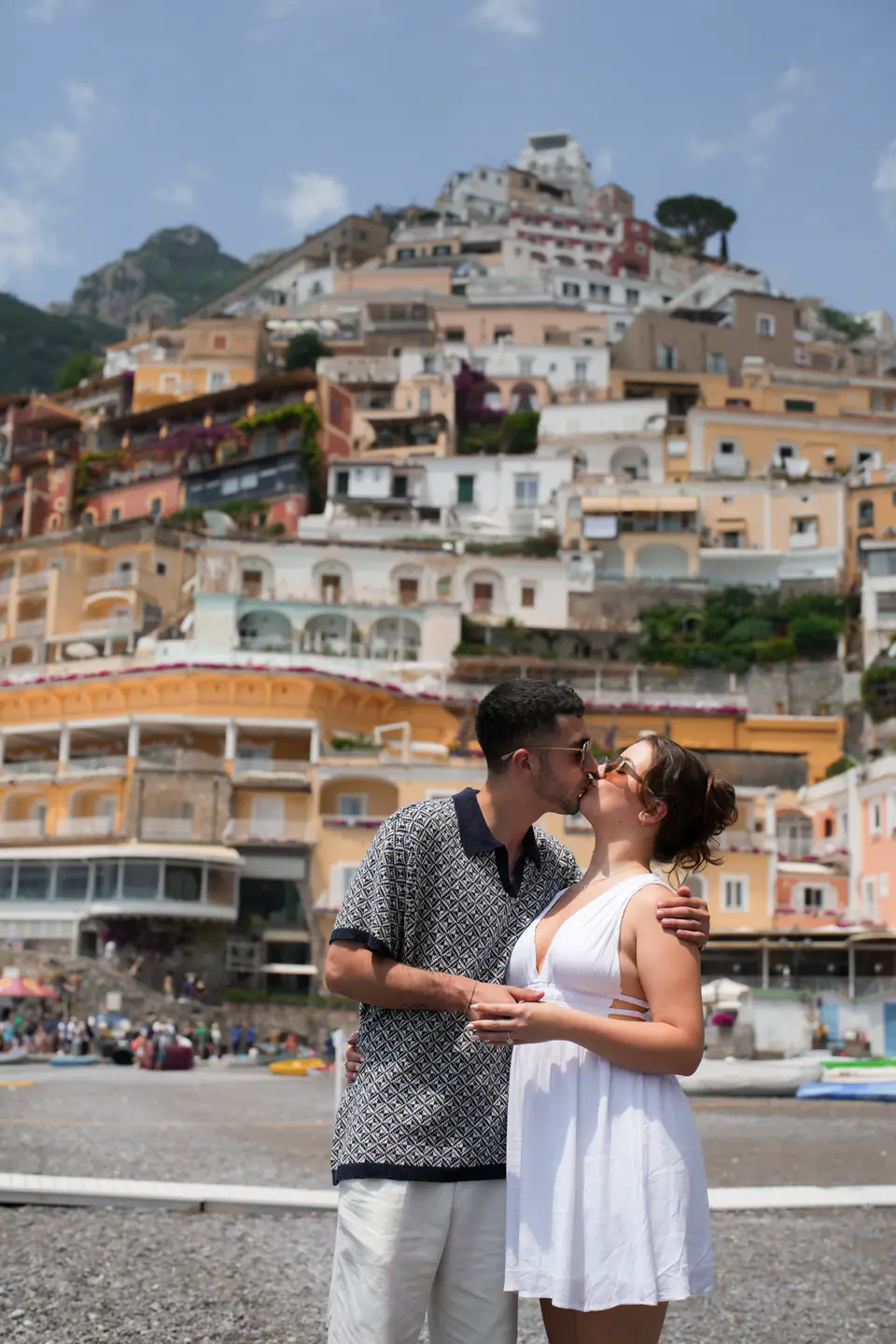 Couple kissing on the beach, the houses of Positano behind them.