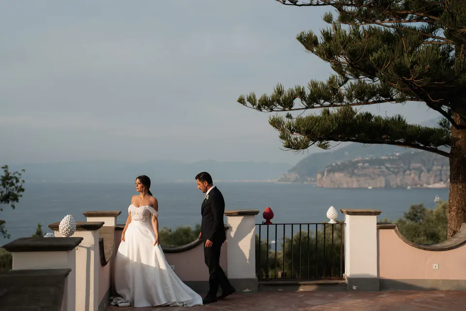 Bride and groom on a terrace above the sea, an umbrella pine and the coast behind