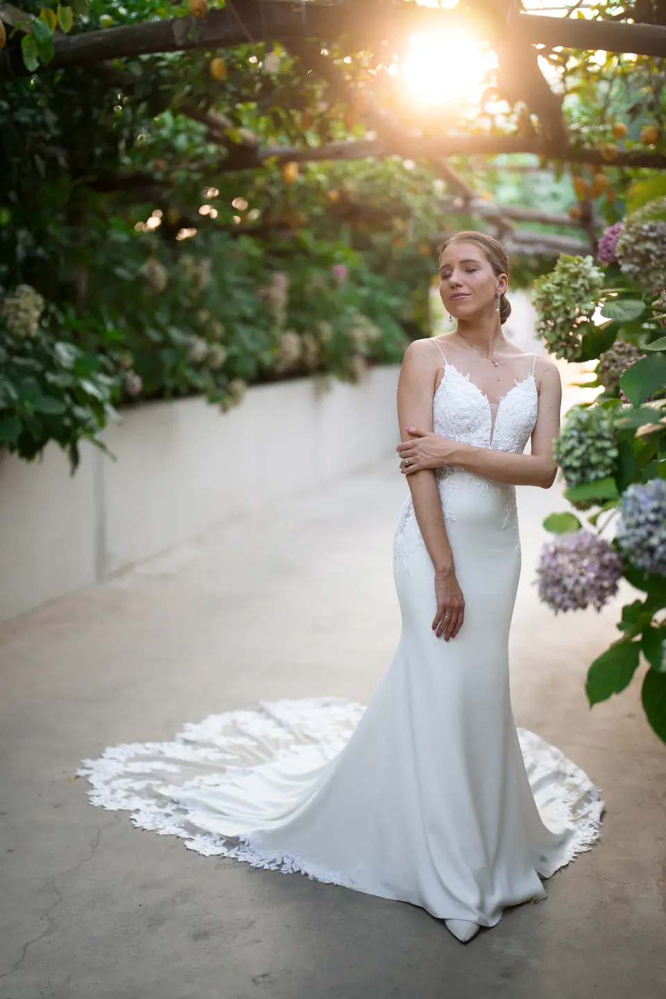 Bride under the lemon pergola, the sun shining through the leaves.