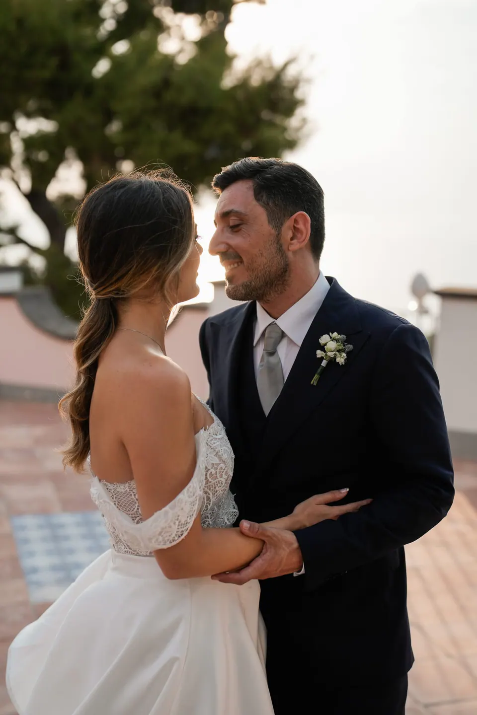 Groom holding the bride close outdoors.