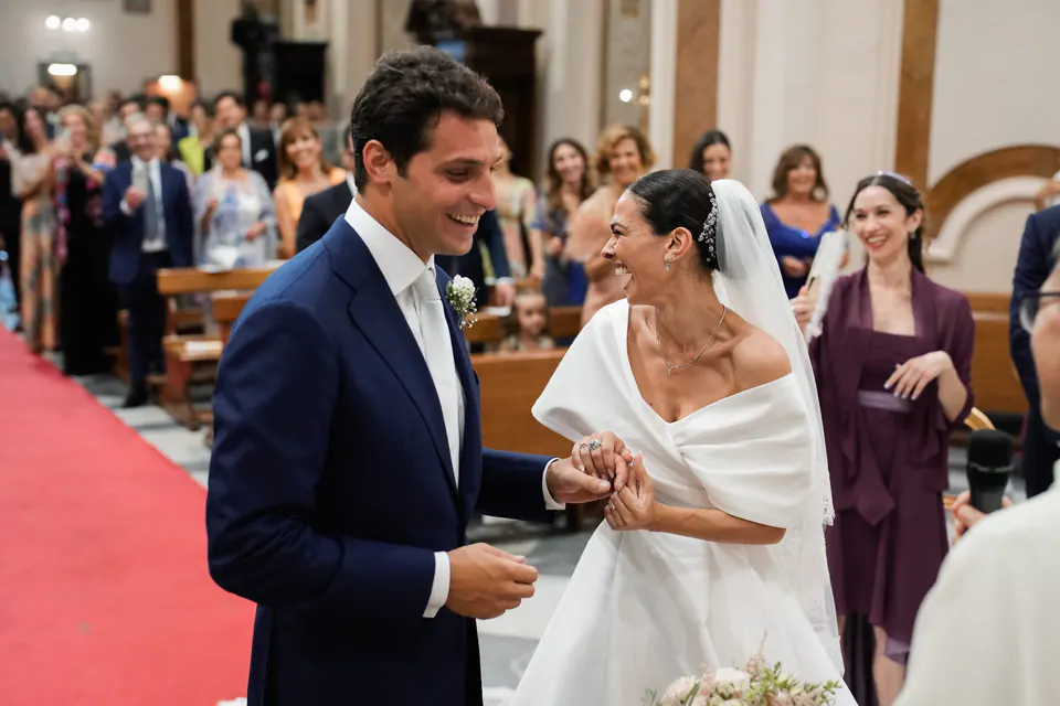Sposi che percorrono la navata da marito e moglie, gli invitati festeggiano intorno.
