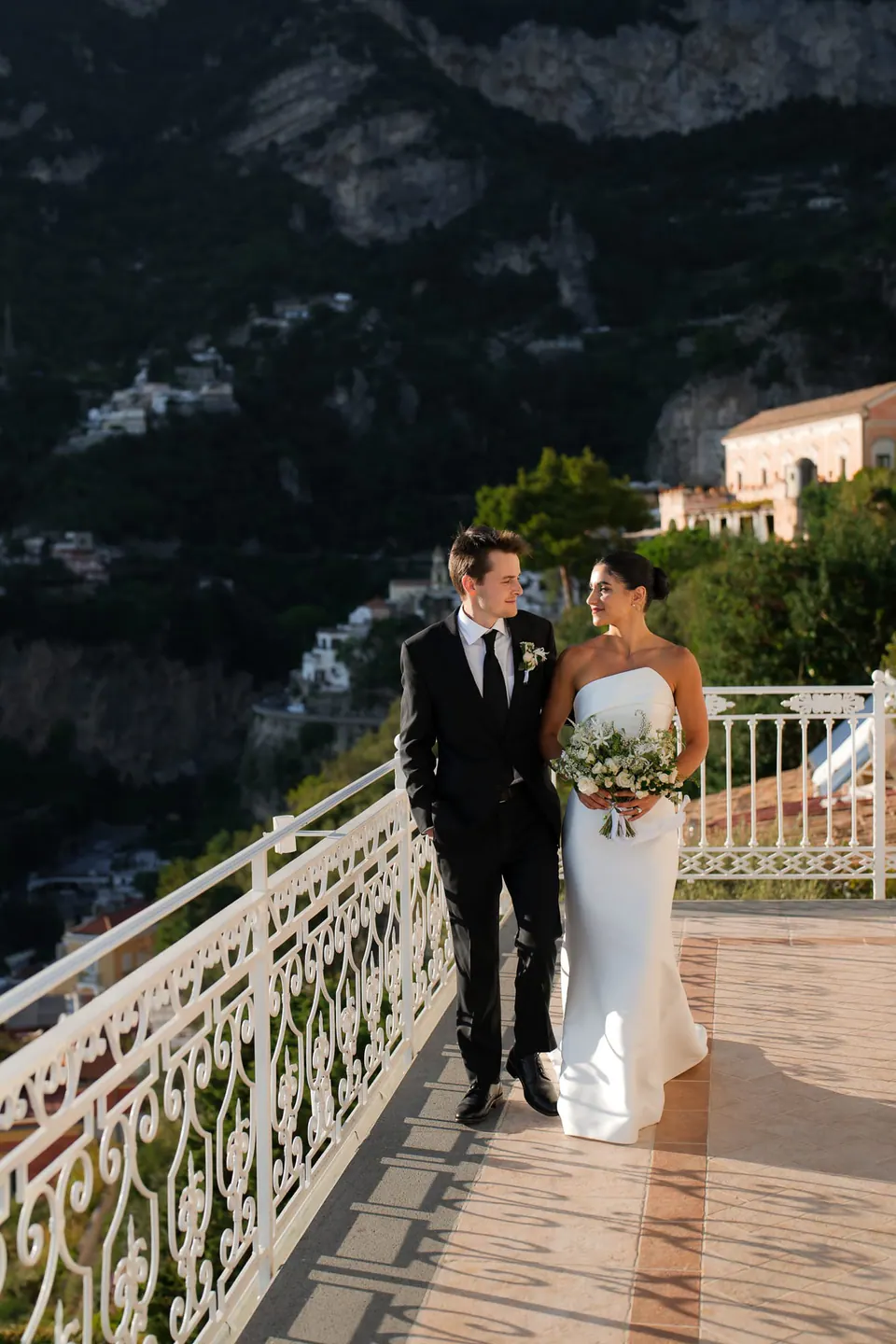 Bride and groom walking along the terrace in the evening light.