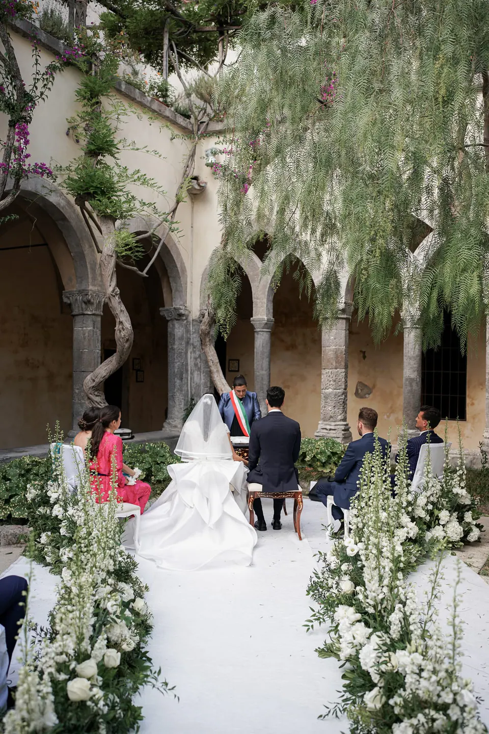 Wedding ceremony in the cloister of San Francesco, the aisle lined with white flowers