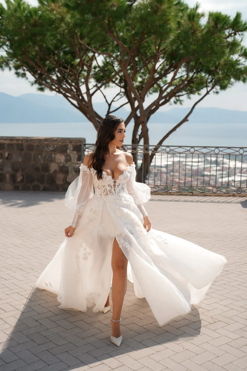 Bride walking across the terrace, the slit of her gown catching the breeze.