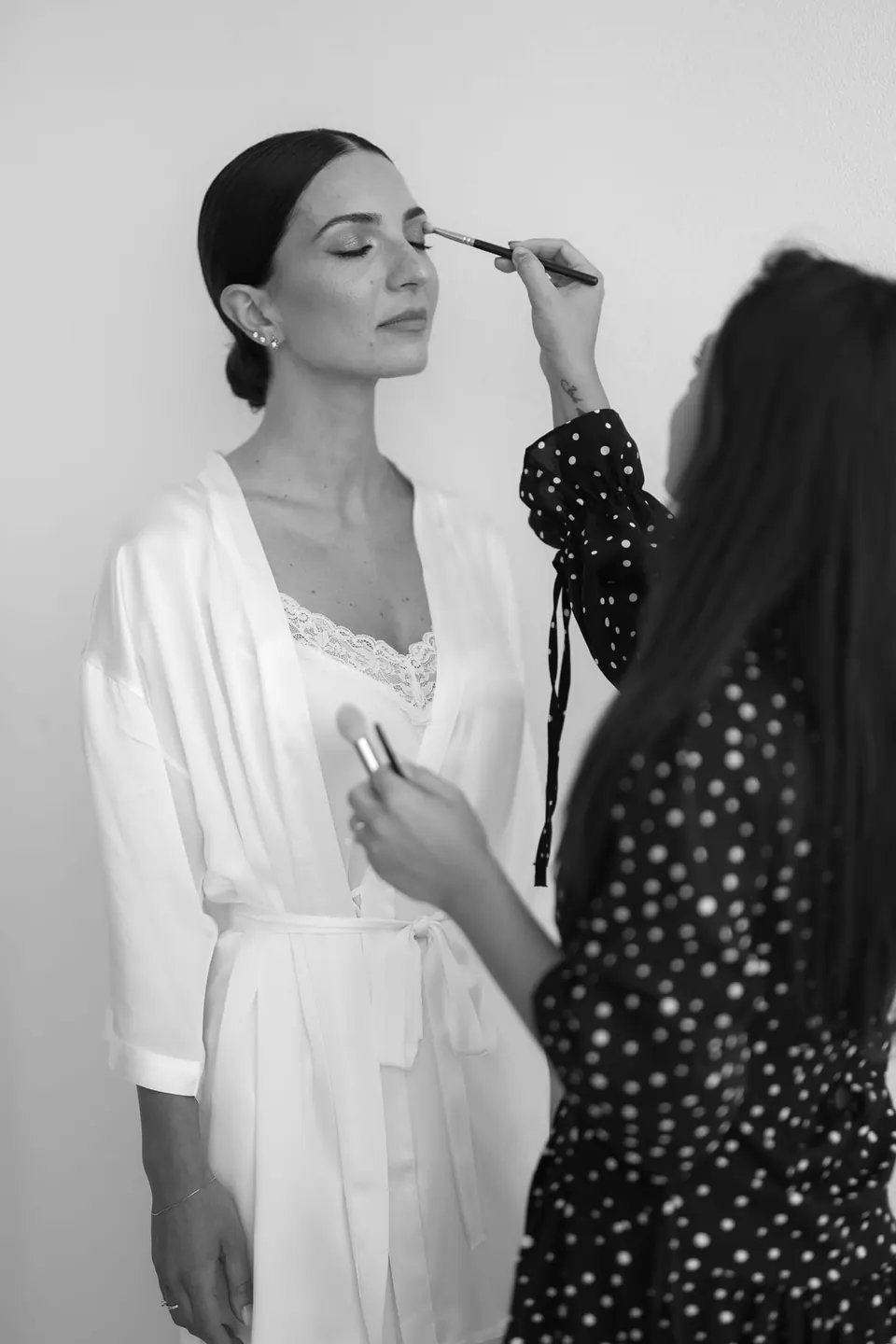 Schwarzweißfoto: Das Augen-Make-up der Braut wird vollendet.