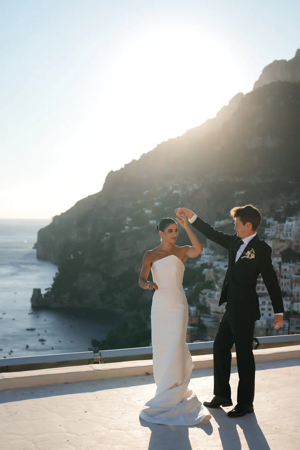 Groom twirling the bride on the terrace, the coast of Positano behind them.